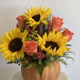 Sunflowers and coral roses arranged in a pumpkin-shaped vase