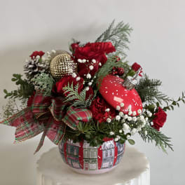 Red roses in a festive holiday arrangement with ornaments in a decorative pot