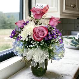 Pink roses and white chrysanthemums in a glass vase with a ribbon bow