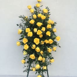 Tall standing arrangement of yellow roses on a metal easel