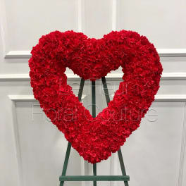 Red carnation heart-shaped standing floral wreath on an easel