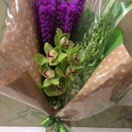 Bouquet of green orchids and purple flowers wrapped in polka-dot paper