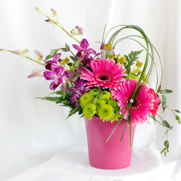 Pink gerbera daisies and purple orchids in a pink vase