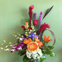 Colorful mixed bouquet in a glass vase with lilies, roses, and orchids