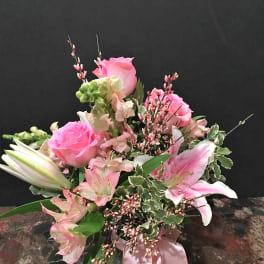 Pink roses and lilies in a glass vase with a pink ribbon