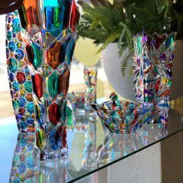 Colorful glass vases on a shelf with a potted fern