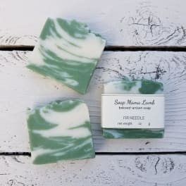 Three green-and-white soap bars on a white wooden surface