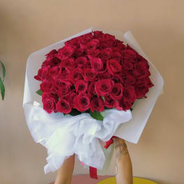 Large bouquet of red roses wrapped in white paper with a ribbon