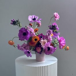 A small vase arrangement of purple, pink, and orange flowers