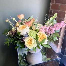Mixed bouquet of peach and cream roses in a gray vase