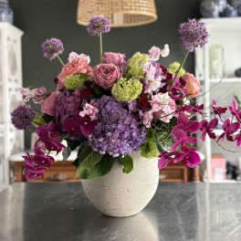 Pink and purple floral arrangement in a white vase