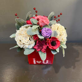Bouquet of pink, red, purple, and cream flowers in a red vase