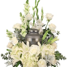 White funeral urn surrounded by white flowers and greenery