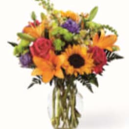 Bouquet of sunflowers, roses, and purple flowers in a glass vase