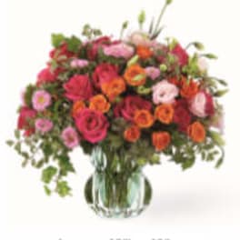 Mixed pink, orange, and red flowers in a glass vase