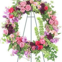 Standing wreath of pink and red roses with mixed purple flowers on a metal easel