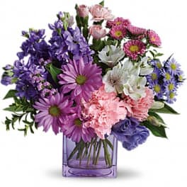 Purple, pink, and white mixed flowers in a square glass vase