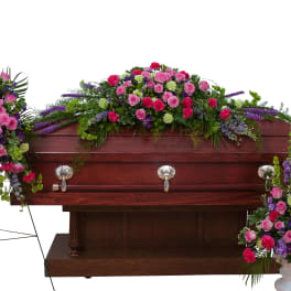 Casket spray and matching standing floral sprays in pink, purple, and green