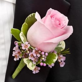 Pink rose boutonniere with small lavender flowers on a black jacket