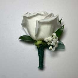 White rose boutonniere with small white filler flowers and green ribbon wrap