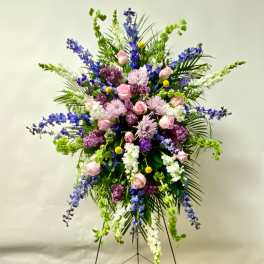 Large standing floral spray with pink roses, purple blooms, and white flowers