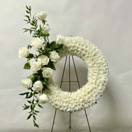 White floral wreath with roses on a black stand