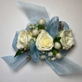 White rose corsage with pale blue ribbon and small berry accents