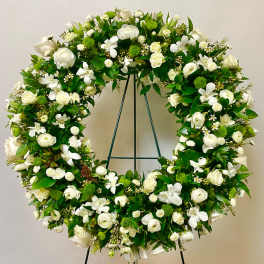 Large white and green floral wreath on a metal stand