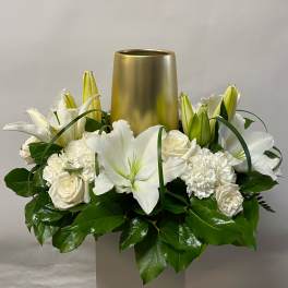 White lilies and roses arranged around a gold vase