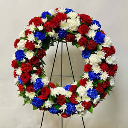 Red, white, and blue floral wreath on a black stand
