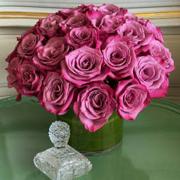 Pink rose bouquet in a green glass vase with a crystal figurine in front