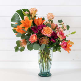 Mixed bouquet of orange and pink flowers in a glass vase