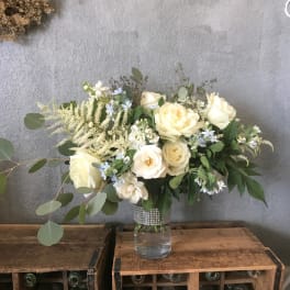 Cream rose bouquet in a clear glass vase with mixed greenery