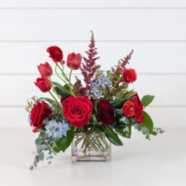 Red roses and tulips arranged in a clear square vase