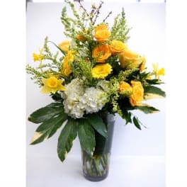 Yellow flowers and white hydrangea in a clear glass vase