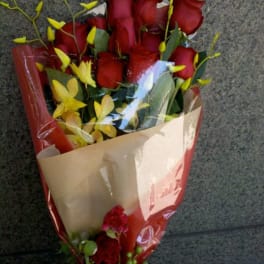Bouquet of red roses with yellow orchids wrapped in paper