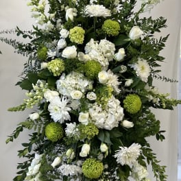 Tall white and green funeral spray on a stand
