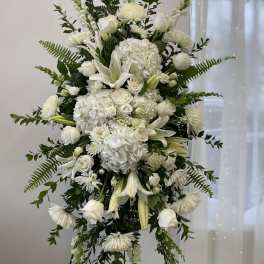White funeral spray with lilies, roses, and hydrangeas on a stand