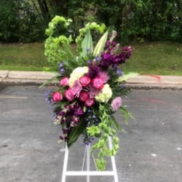 Tall floral spray with pink, purple, and green blooms on a white stand