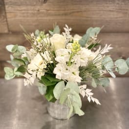 White floral arrangement in a ribbed metal vase with pale greenery