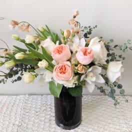Bouquet of blush roses and white orchids in a dark vase