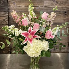 Pink roses and a pink stargazer lily in a glass vase