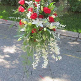 Tall floral spray with red roses, white lilies, and cascading white flowers