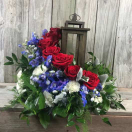Red roses and blue flowers arranged around a lantern