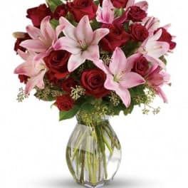Bouquet of red roses and pink lilies in a clear glass vase