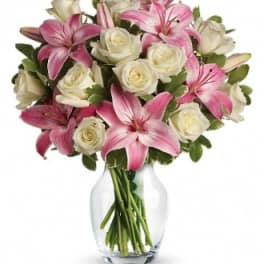 Pink lilies and white roses arranged in a clear glass vase