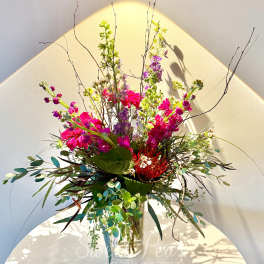 Tall mixed bouquet in a clear glass vase with bright pink and purple blooms