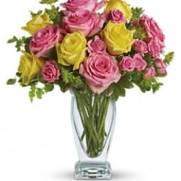 Pink and yellow roses arranged in a clear glass vase