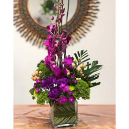 Purple orchid arrangement in a square glass vase