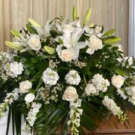 Large white floral spray with lilies and roses on a casket